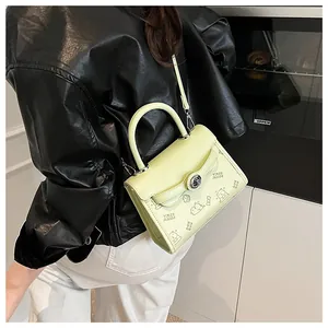 Close-up of light green crossbody bag with cartoon print and metal twist lock