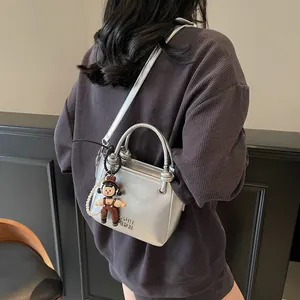 Silver metallic bucket bag with cute bear charm worn over a dark grey textured shirt