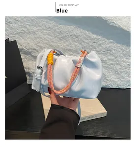 Detail of light blue cloud bag with pleated design and woven handle on stone background