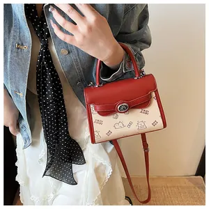Detail of red and white crossbody bag with cute bear prints and metal turn lock
