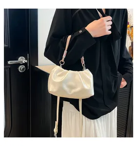 Detail of creamy white ruched cloud bag featuring pink woven handle and metal ring