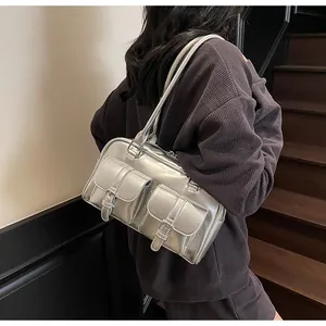 Detail of silver metallic tote bag featuring double buckle pockets and shoulder straps