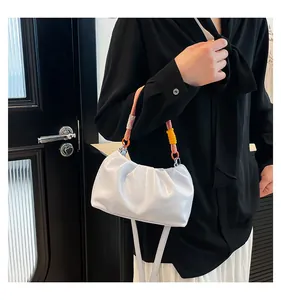 Detail of white ruched cloud bag featuring a vibrant three-color braided handle and strap