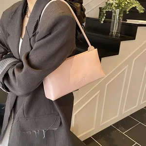 Chic light pink rectangular underarm bag with thin straps and metallic ball accents