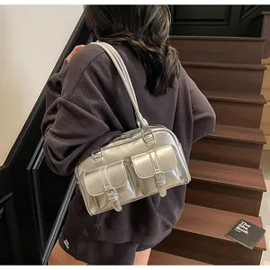 Detail of silver shoulder bag with metallic finish and two front buckle pockets