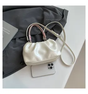 Close-up of beige ruched cloud bag with woven handle and smooth pearlescent texture