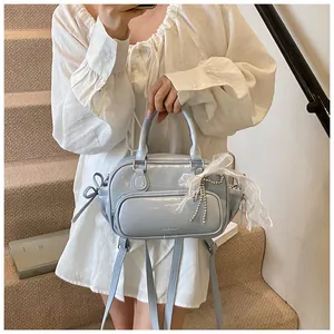 Detalle de bolso azul claro con lazos de encaje blanco y colgantes de cuentas de plata