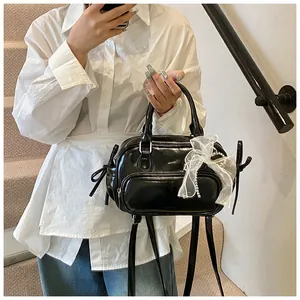Primer plano del bolso de charol negro con lazos de encaje y adornos de perlas finas