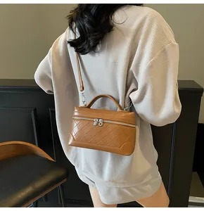 Detail of brown quilted crossbody bag featuring dual zippers and top handle