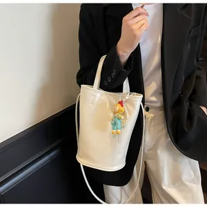 Detail van witte leren bucket bag met fashion logo, parelketting en schattige hanger