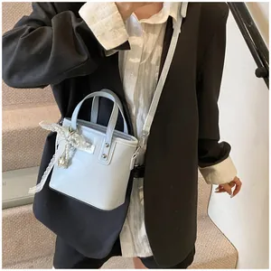Dettaglio borsa in PU azzurro con fiocco di pizzo e pendente di perle elegante