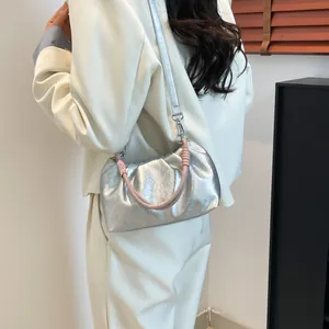 Metallic silver ruched cloud bag with pink braided handle shown on model's shoulder