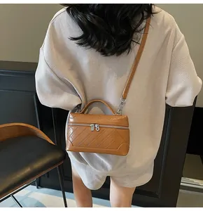 Rear view of a model carrying a caramel brown leather shoulder bag with quilted texture