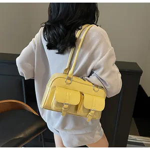 Detailed side view of yellow faux leather underarm tote bag worn by a model