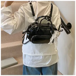 Detalle de mini mochila de charol negro con bufanda de encaje y cremallera plateada