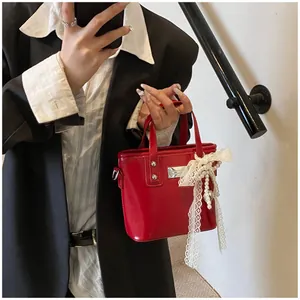Dettaglio mini borsa in pelle verniciata rossa con fiocco in pizzo e perle