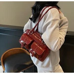 Detail view of deep burgundy patent leather shoulder bag with metallic buckle pockets