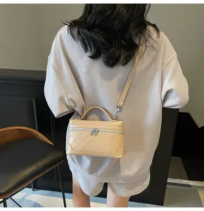 Detail of a beige quilted crossbody bag with top handle and silver metal strap hardware