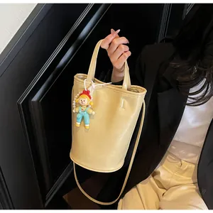 Detail van lichtgele emmertas met fashion-logo en schattige cartoon pop als hanger
