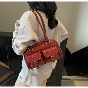 Close-up of deep red glossy patent leather tote bag with silver metal buckle details