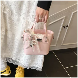 Dettaglio della borsa in ecopelle rosa con fiocco in pizzo e ciondolo di perle