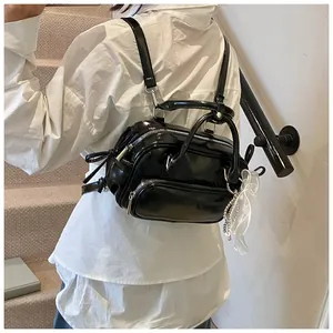 Detalle de mini mochila negra brillante con lazo de encaje y cadena de cuentas plata