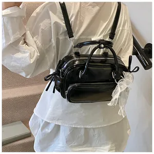 Detalle de la mochila negra de cuero sintético con cremalleras plateadas y lazo blanco