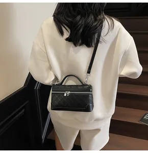 Rear view of model carrying a black quilted vanity bag with silver hardware on stairs