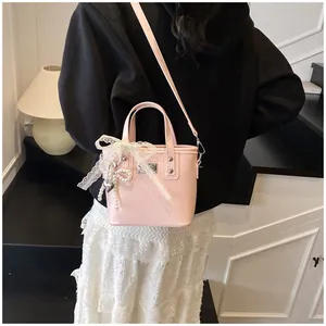 Dettaglio della borsa rosa con fiocco di pizzo, perle e ciondolo a cuore su modella