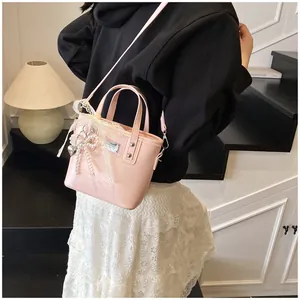 Dettaglio borsa rosa con finiture in pizzo, perle e ciondolo a forma di cuore