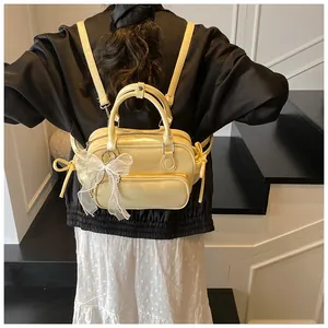 Detalle de mochila de cuero amarillo crema con lazo de encaje blanco y correas dobles
