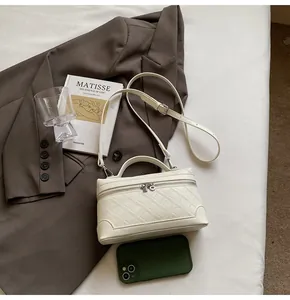 Flat lay of cream quilted box bag with silver zipper and adjustable strap