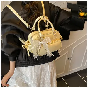 Detalle de mochila de cuero amarillo crema con un lazo de encaje blanco y perla