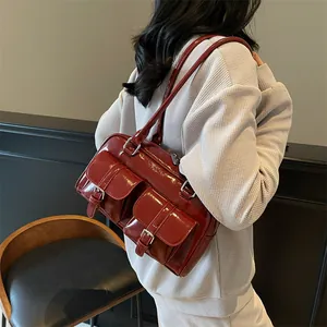 Deep red glossy patent leather tote bag with dual front pockets worn on shoulder
