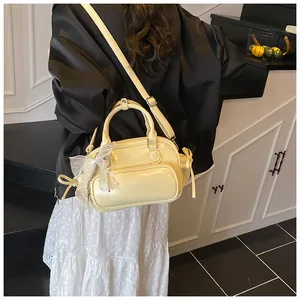 Detalle de bolso de cuero crema con lazo decorativo y colgante floral de encaje para mujer