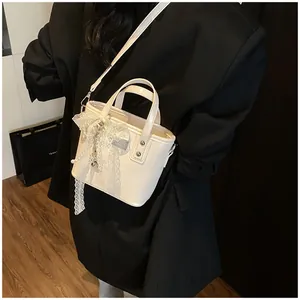 Dettaglio mini borsa bianca con fiocco in pizzo e ciondolo di perla indossata da modella