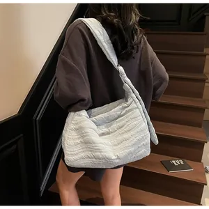 Model wearing a light blue quilted puffer tote bag on a wooden staircase backdrop