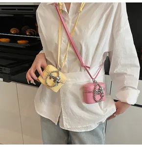 Detail of mini bucket bags in yellow and pink leather with metallic heart charms