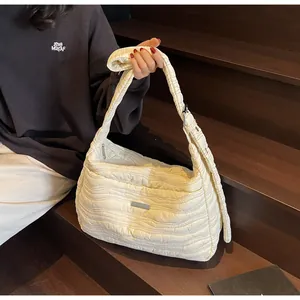 Détail d'un sac fourre-tout matelassé blanc crème avec logo métallique et large bandoulière