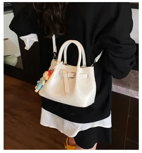 Detail of off-white pleated bucket bag with plush charm and adjustable shoulder strap