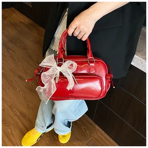 Detalle de mini bolso Boston rojo brillante con lazo de malla y cadena de perlas