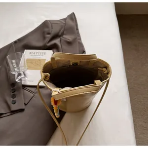 Detailoverzicht van crèmekleurige bucket bag met magneetsluiting en ritsvak binnenin