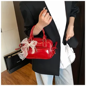 Detalle del bolso de charol rojo con lazo de encaje blanco y flecos brillantes