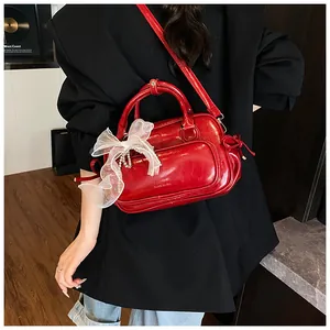 Detalle del bolso Boston de cuero rojo brillante con lazo de encaje y colgante de perlas