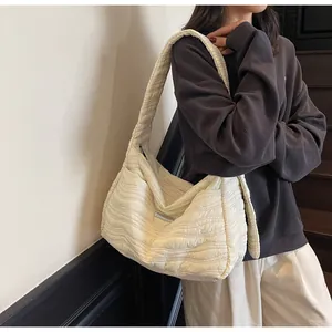 Vue détaillée de la texture matelassée et de la poche latérale du sac fourre-tout crème