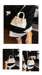 Detail of white PU bucket bag with leather texture and cute clown doll charm accessory