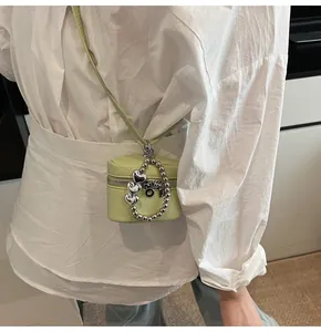 Close-up of lime green pebbled leather mini crossbody bag with silver heart charm and strap