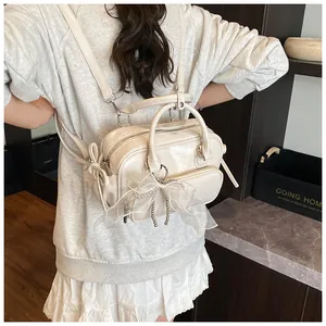 Mochila convertible blanco crema con lazo de encaje decorativo y colgante de perlas