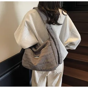 Détail du sac hobo matelassé gris foncé avec larges bretelles et détails d'œillets