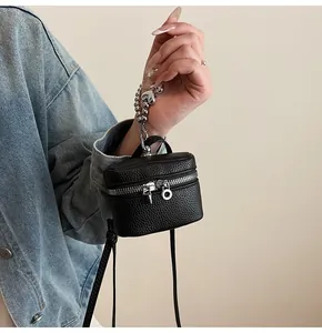 Detail of mini black lychee texture handbag with heart pendant and silver beaded handle
